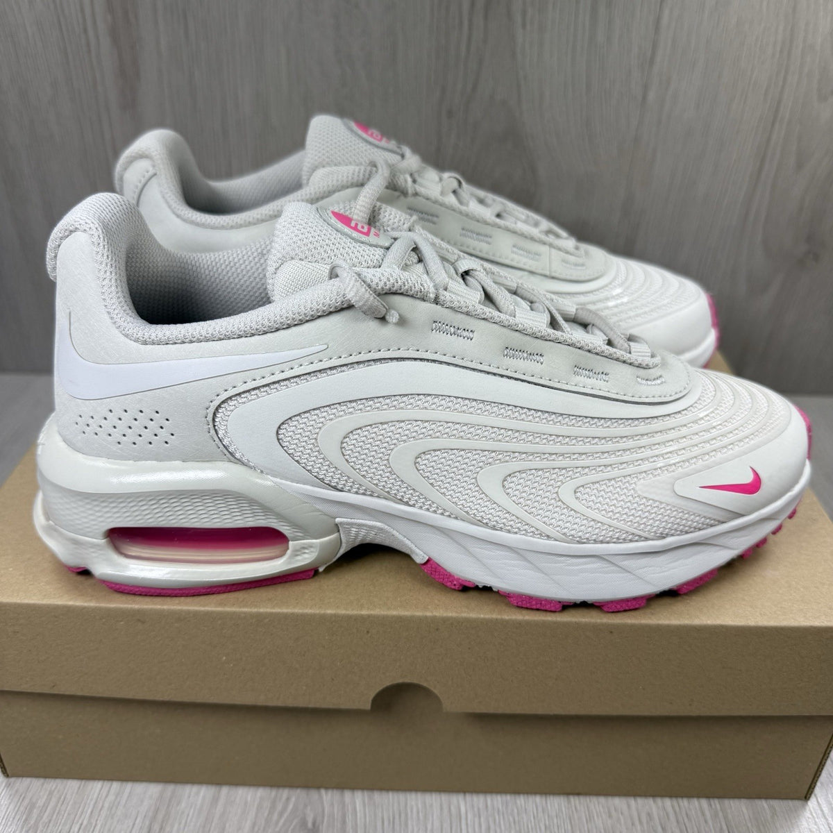 Nike Air Max trainers beige with pink accents and logo detail on the side.