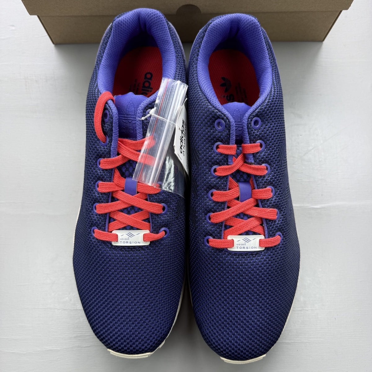 Adidas blue ZX Flux trainers with red and white woven pattern, logo on tongue.
