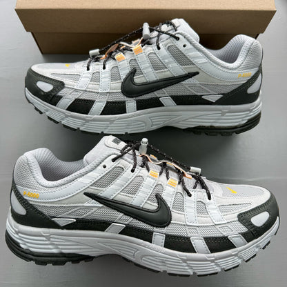 Nike grey P-6000 trainers with laser orange accents and mesh material.