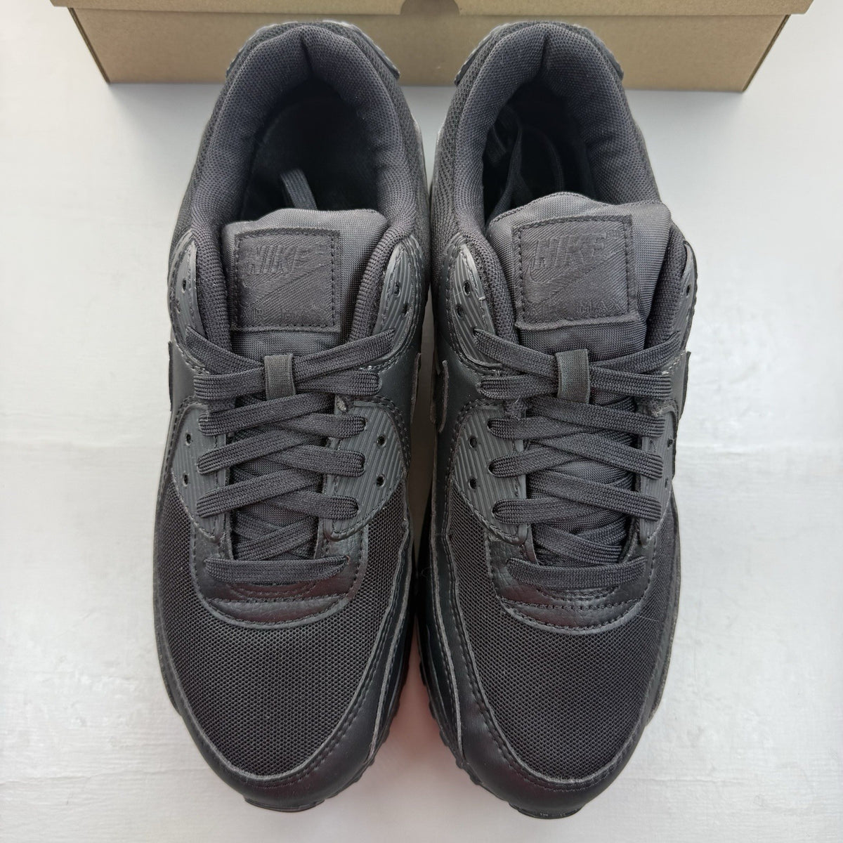 Nike Air Max 90 trainers black with signature logo and textured upper design.