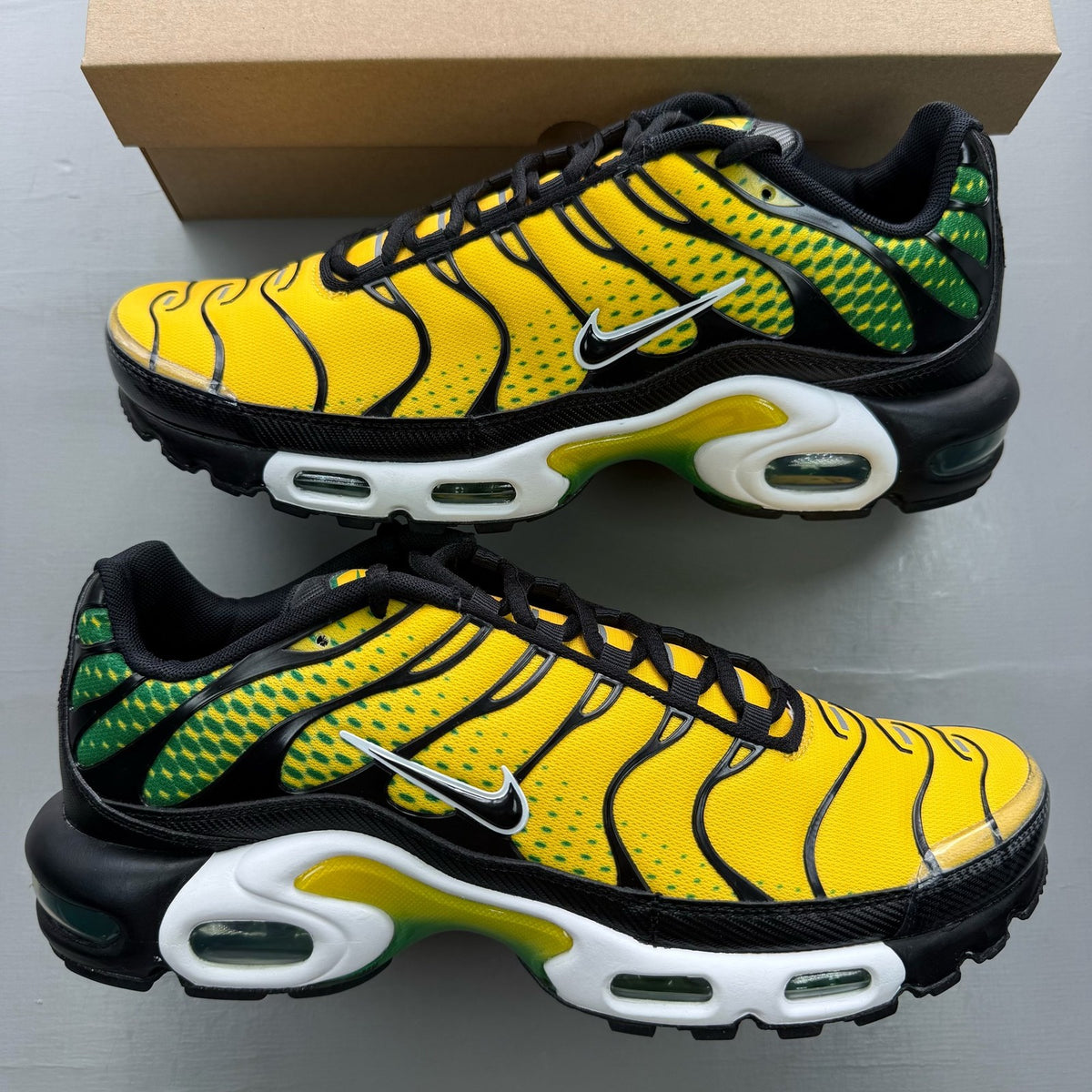 Nike Air Max Plus TN yellow trainers with green accents and signature swoosh logo.