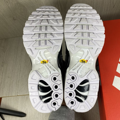 Nike Air Max Plus TN trainers black and white with signature logo and mesh detailing.