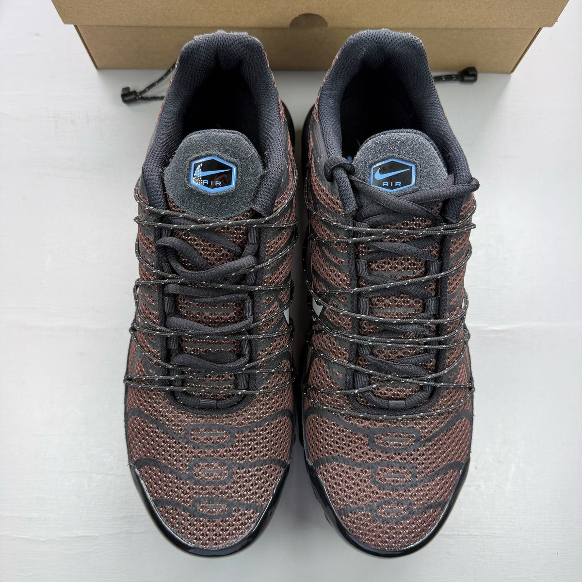 Nike Air Max Plus TN black trainers with distinctive wave pattern and cushioned sole.