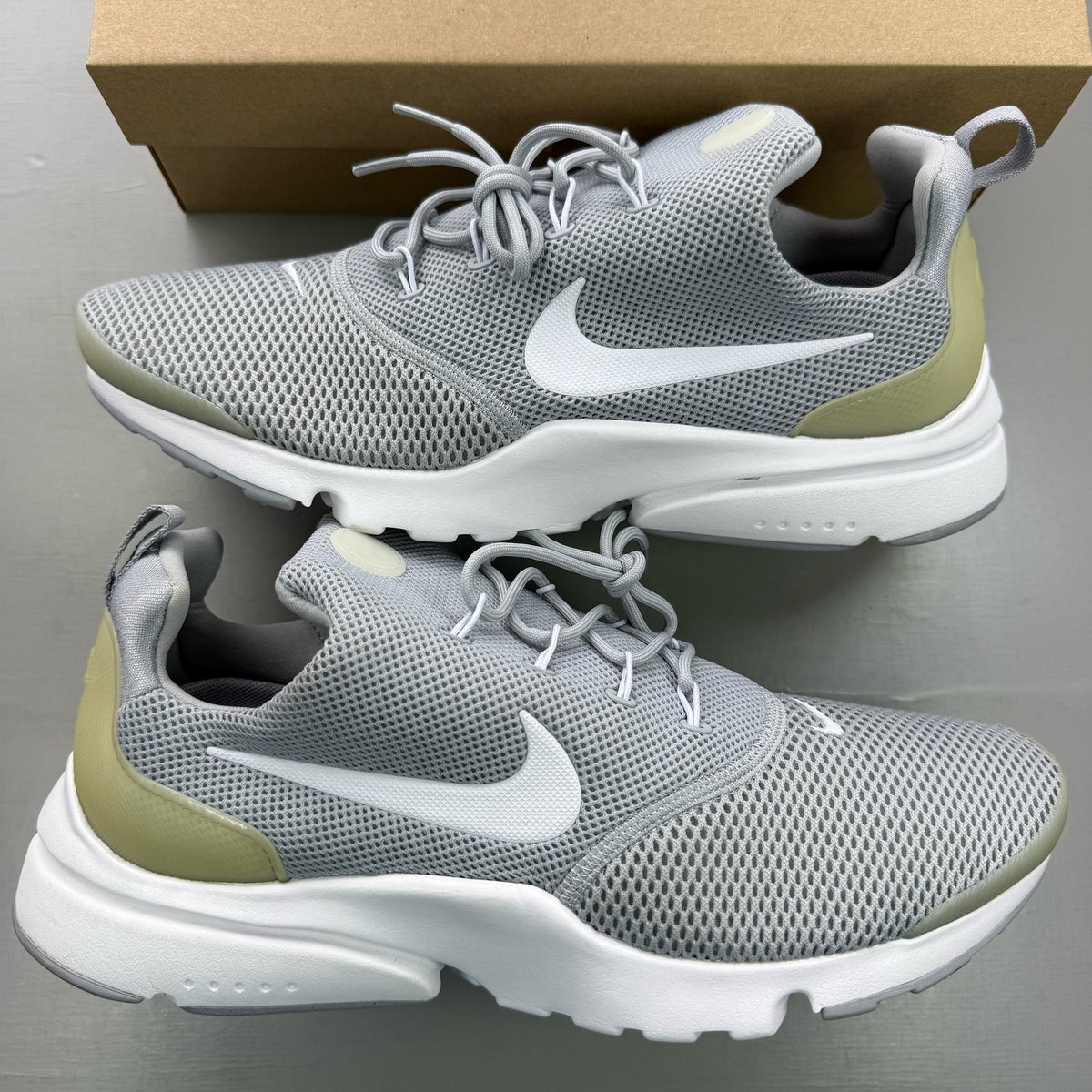 Nike Presto Fly grey trainers with white accents and logo detail.