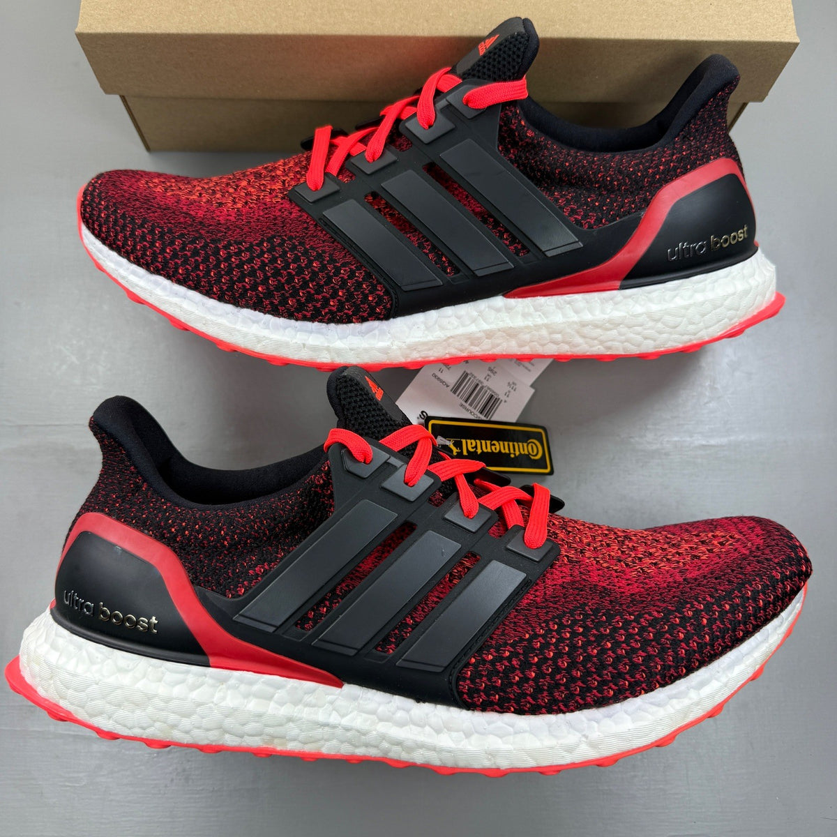 Adidas Ultra Boost 2.0 red trainers with black accents and signature three-stripe logo.