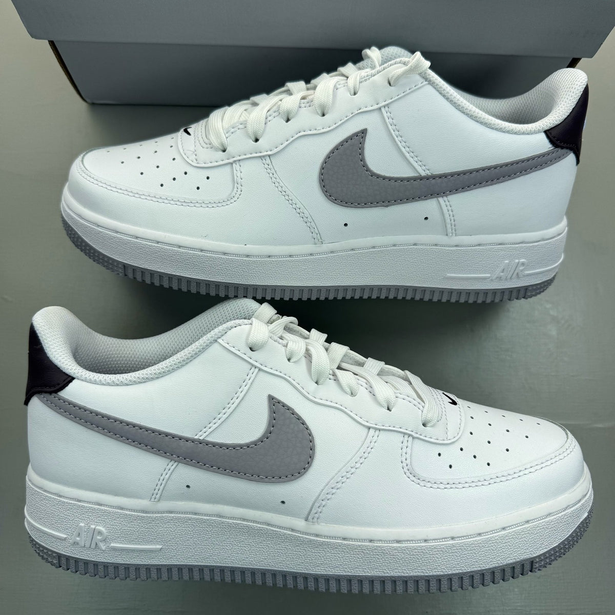 Nike Air Force 1 low white trainers with grey cement accents and logo detailing.