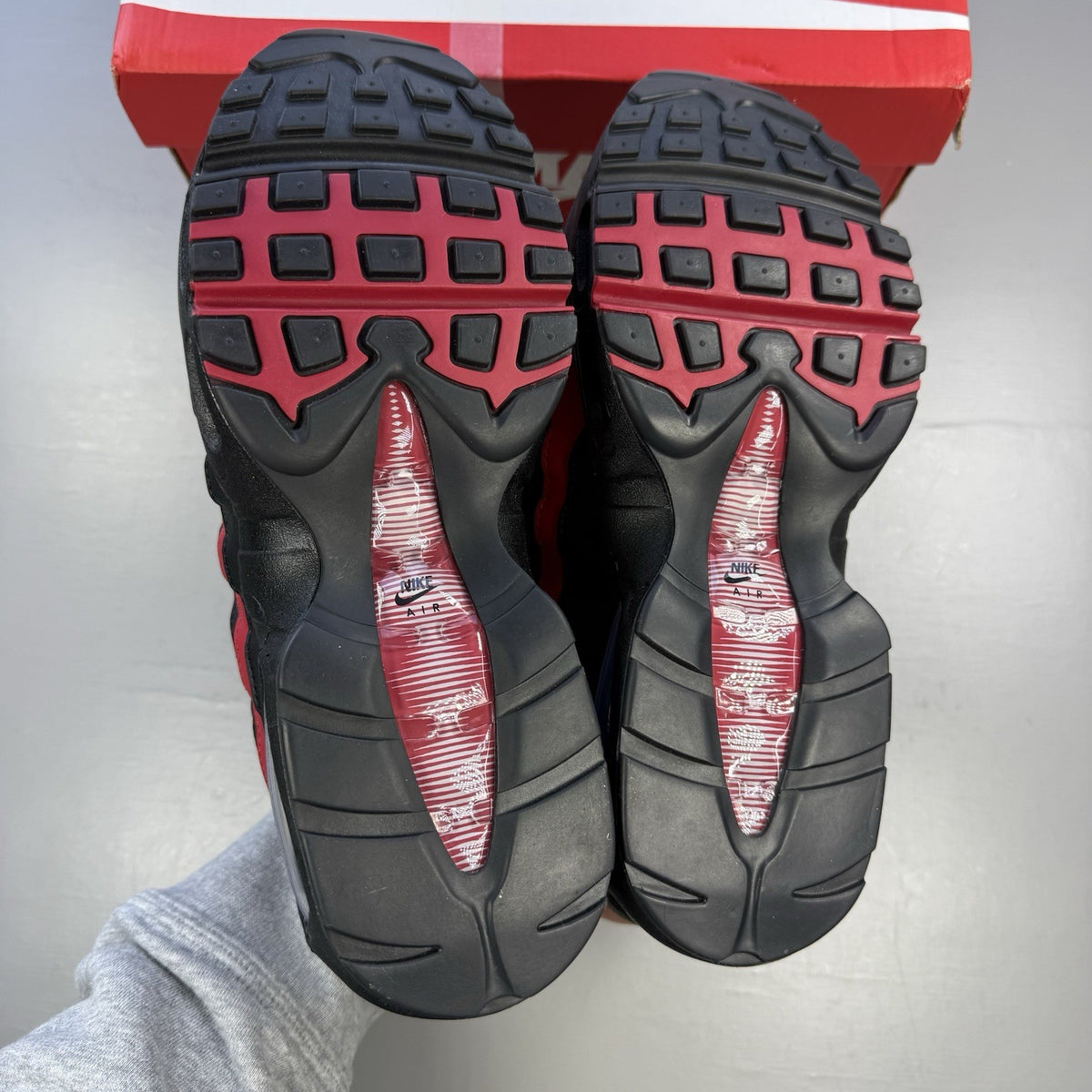 Nike Air Max 95 black trainers with crimson red accents and grey detailing.