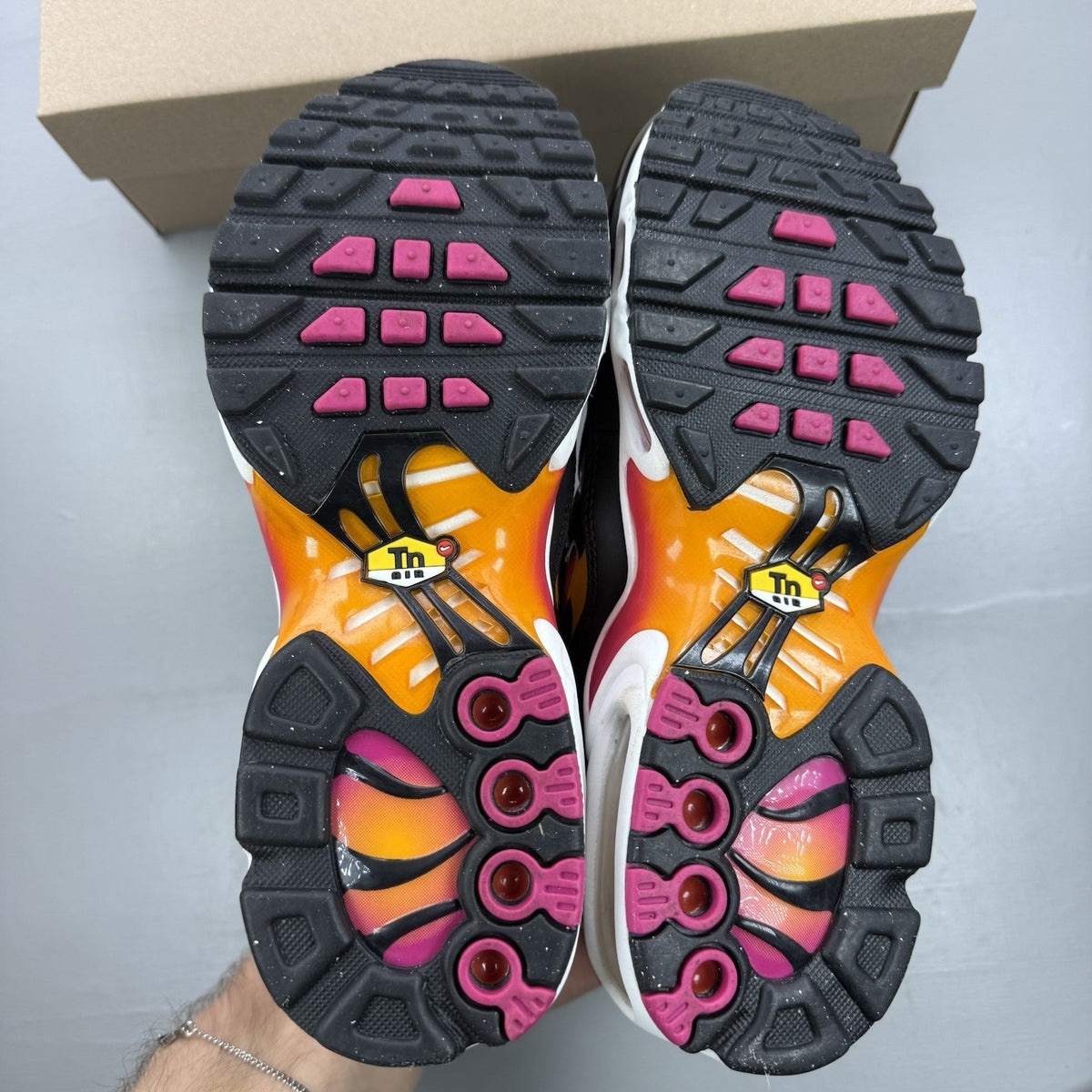 Nike Air Max Plus TN black trainers with active pink and white accents, logo detailing.