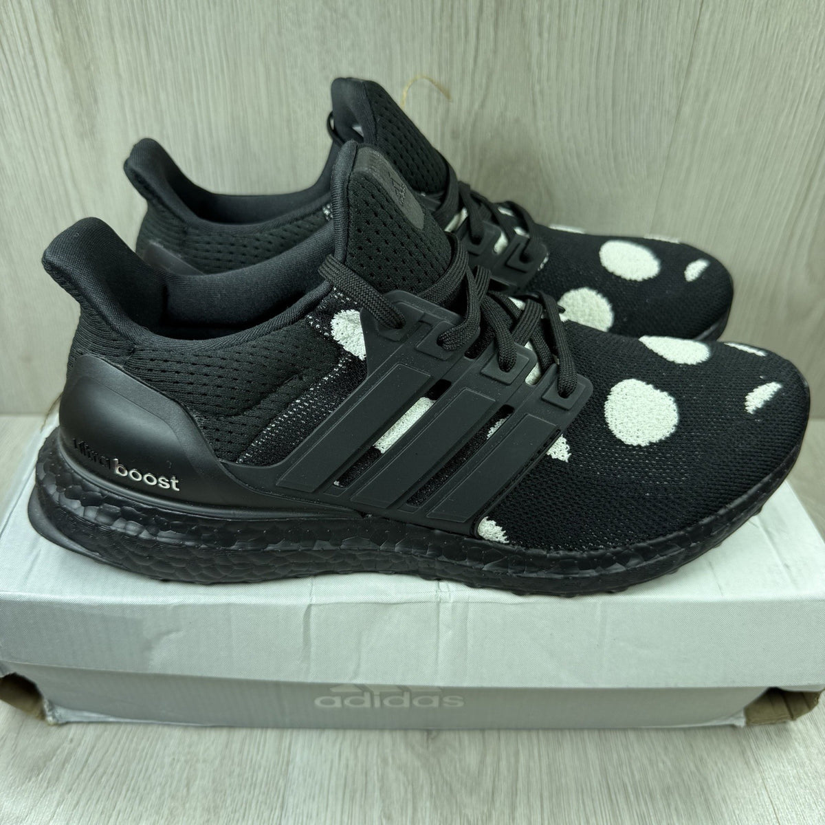 Adidas black trainers with white polka dot pattern and iconic three-stripe logo.