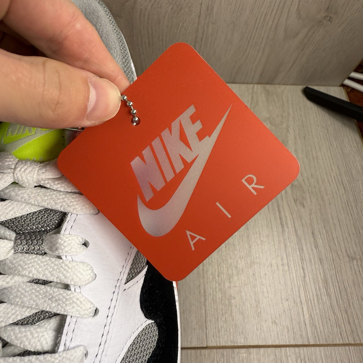 Nike Air Max 1 trainers white with chili volt accents and black detailing.