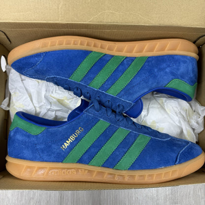 Adidas blue trainers with gum sole and iconic three-stripe logo design.