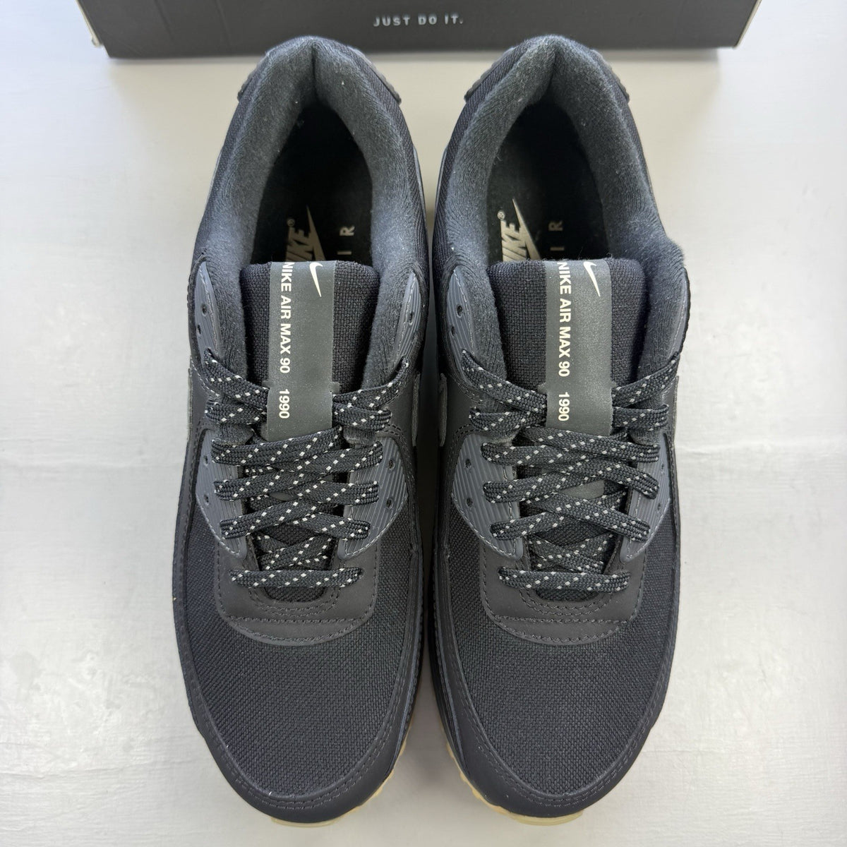 Nike Air Max 90 black trainers with reflective details and gum sole.