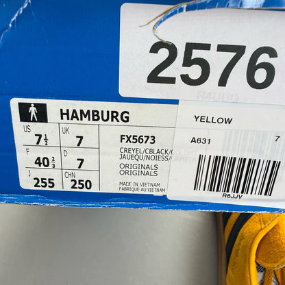 Adidas yellow trainers with black and gold accents, featuring iconic logo detail.