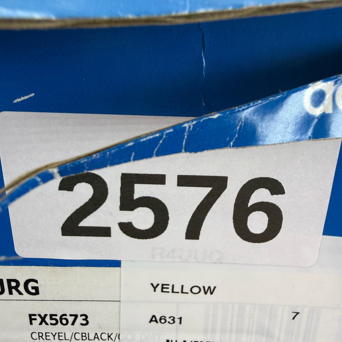 Adidas yellow trainers with black and gold accents, featuring iconic logo detail.