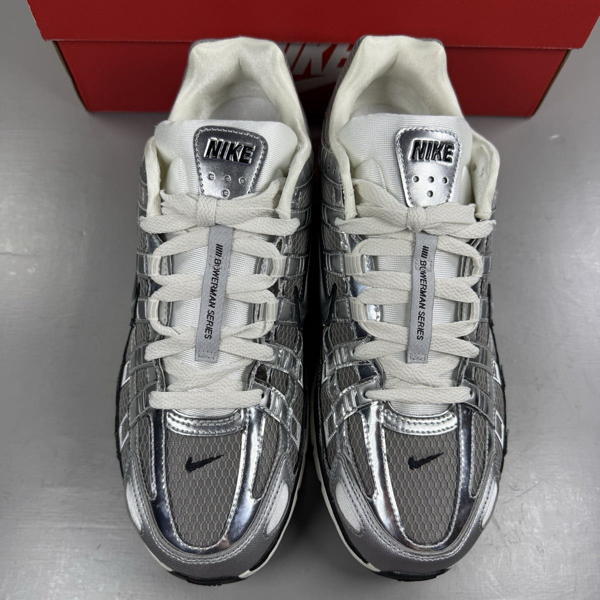 Nike P-6000 metallic silver trainers with black accents and white detailing.