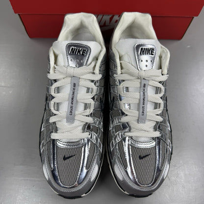 Nike P-6000 metallic silver trainers with black accents and white detailing.