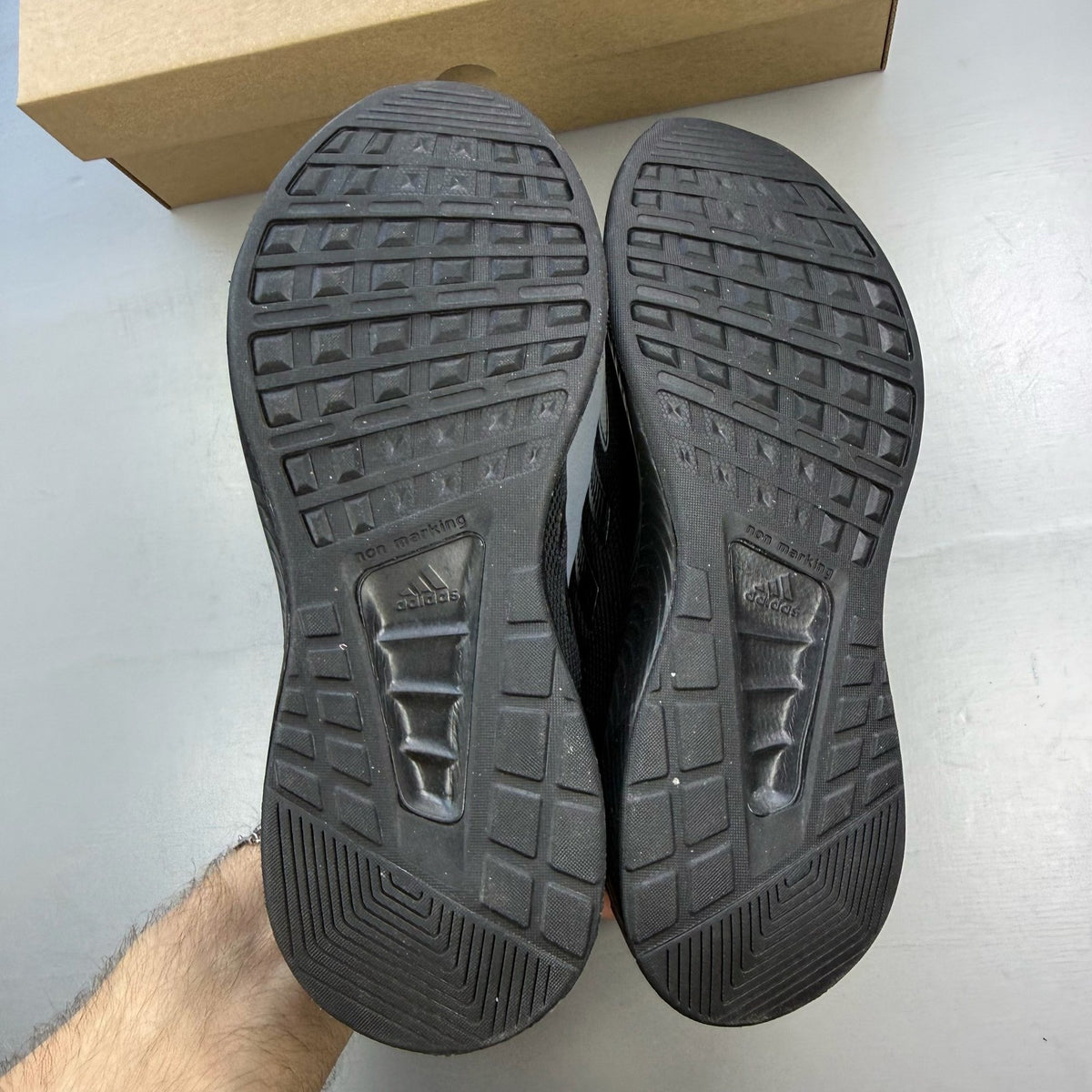 Adidas black trainers with signature three stripes and cushioned sole.