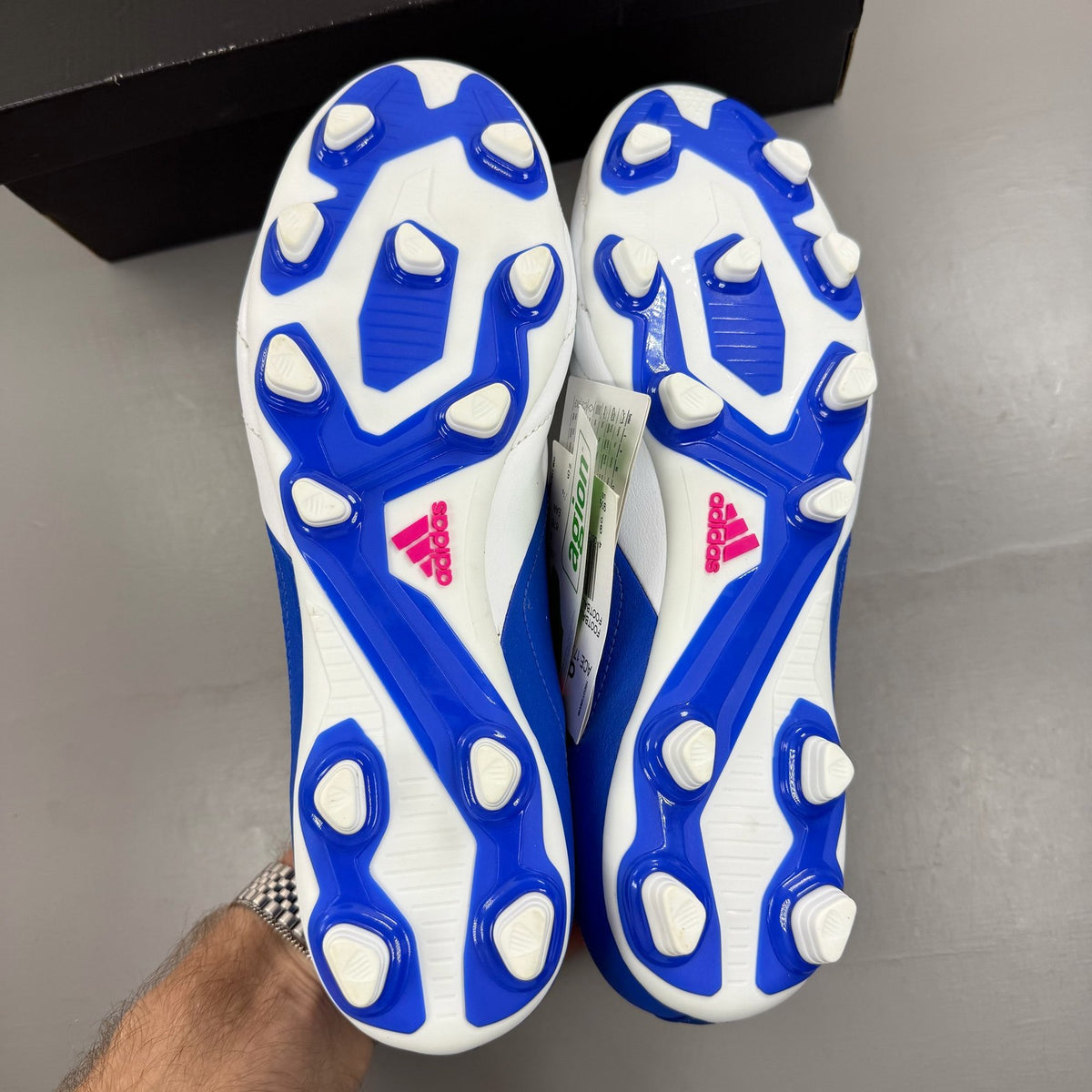 Adidas football boots white with blue and pink accents, featuring logo and textured material.