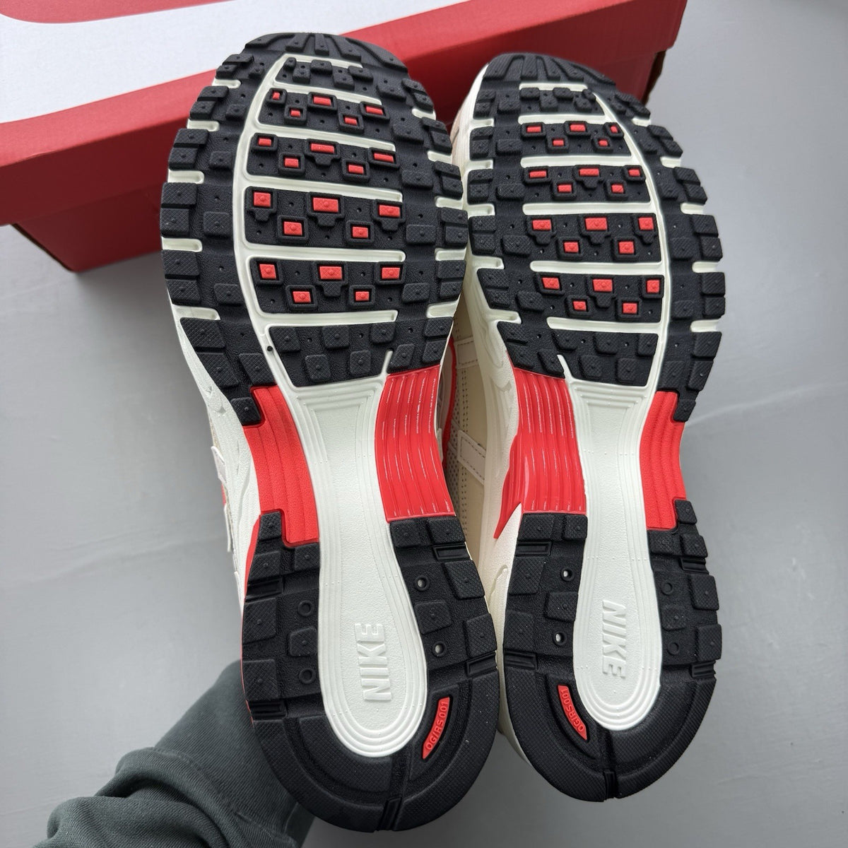 Nike white trainers with bright crimson red accents and soft pearl cream detailing.