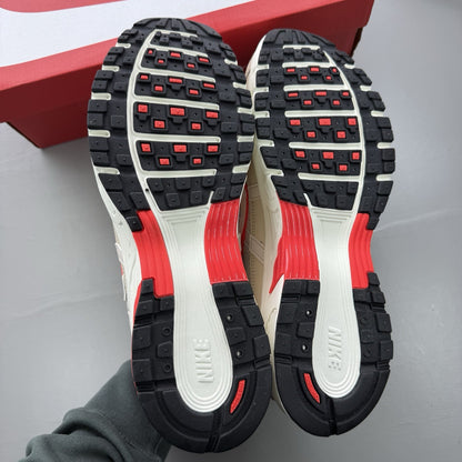 Nike white trainers with bright crimson red accents and soft pearl cream detailing.