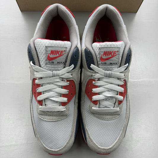 Nike Air Max 90 trainers white with red and navy accents, featuring logo details.