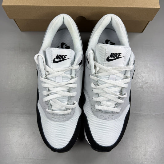 Nike Air Max 1 white trainers with black and grey accents, featuring logo details.