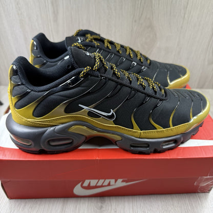 Nike Air Max Plus TN trainers black with gold accents and distinctive wavy pattern.