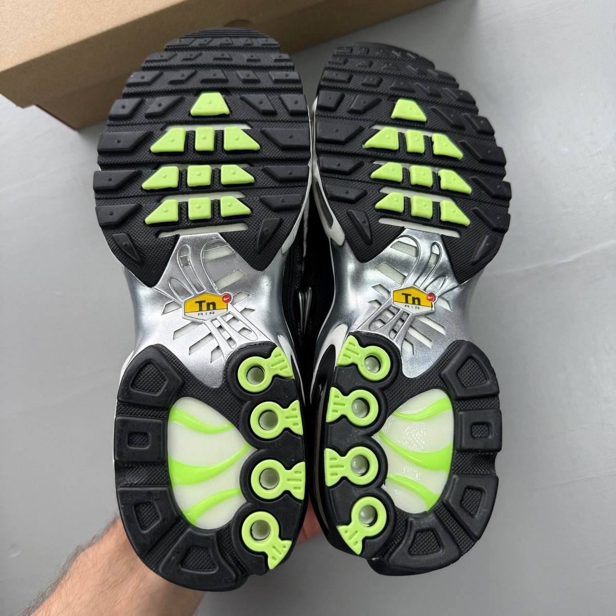 Nike Air Max Plus TN black trainers with chrome accents and distinctive wave pattern.