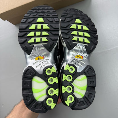 Nike Air Max Plus TN black trainers with chrome accents and distinctive wave pattern.