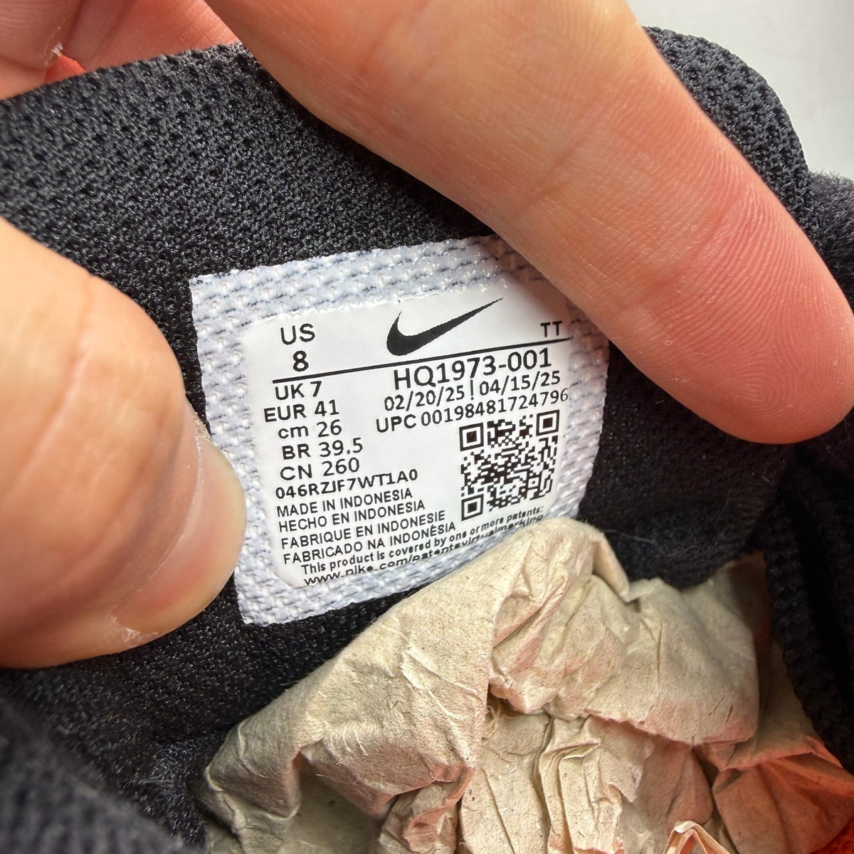 Nike Air Max 95 black trainers with orange camo accents and logo details.