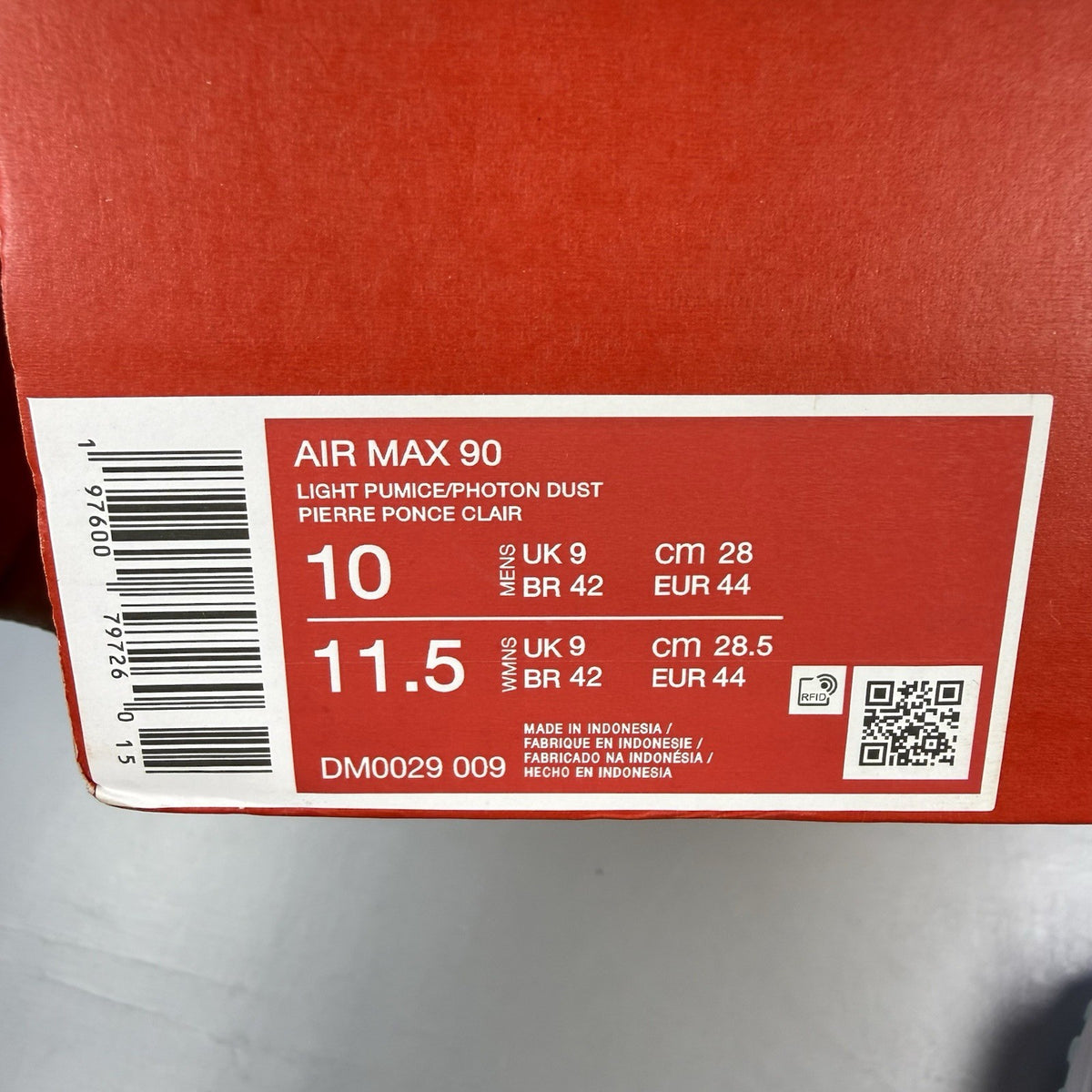 Nike Air Max 90 grey trainers with blue and white accents, featuring iconic logo.
