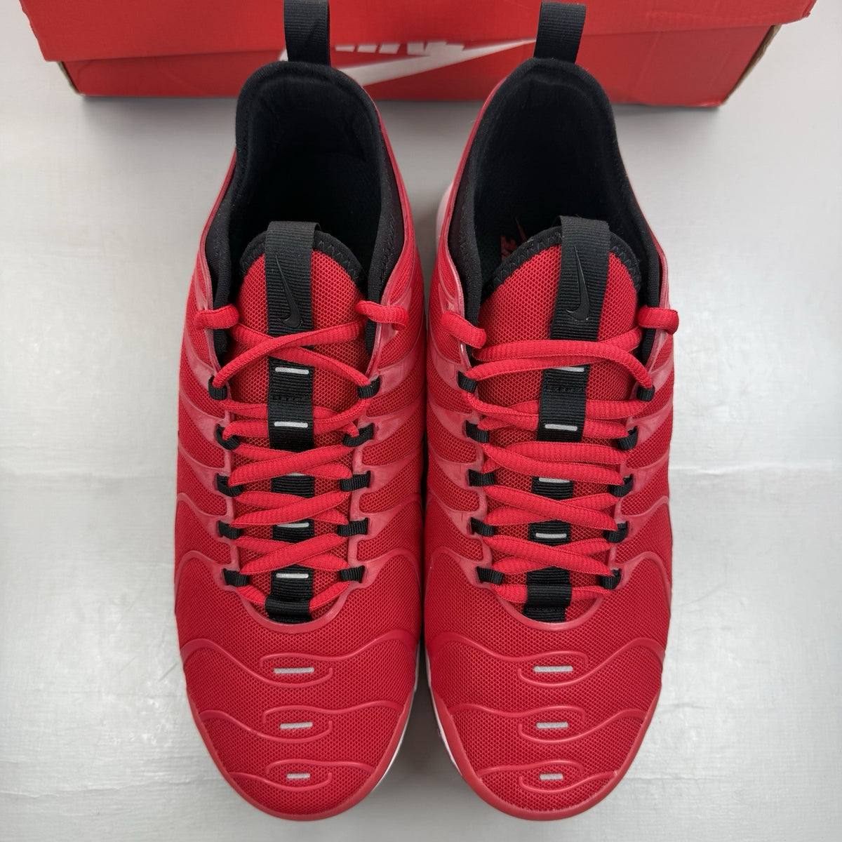 Nike Air Max Plus TN Ultra red trainers with black accents and signature logo.