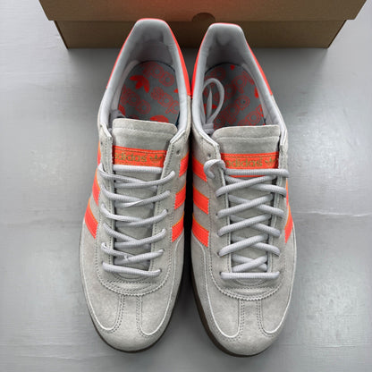 Adidas grey trainers with coral accents and gum sole, featuring classic logo.