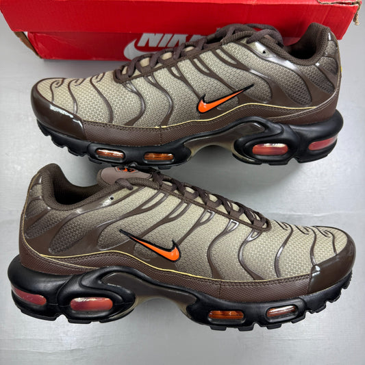 Nike Air Max Plus TN brown athletic shoes with safety orange accents and logo details.