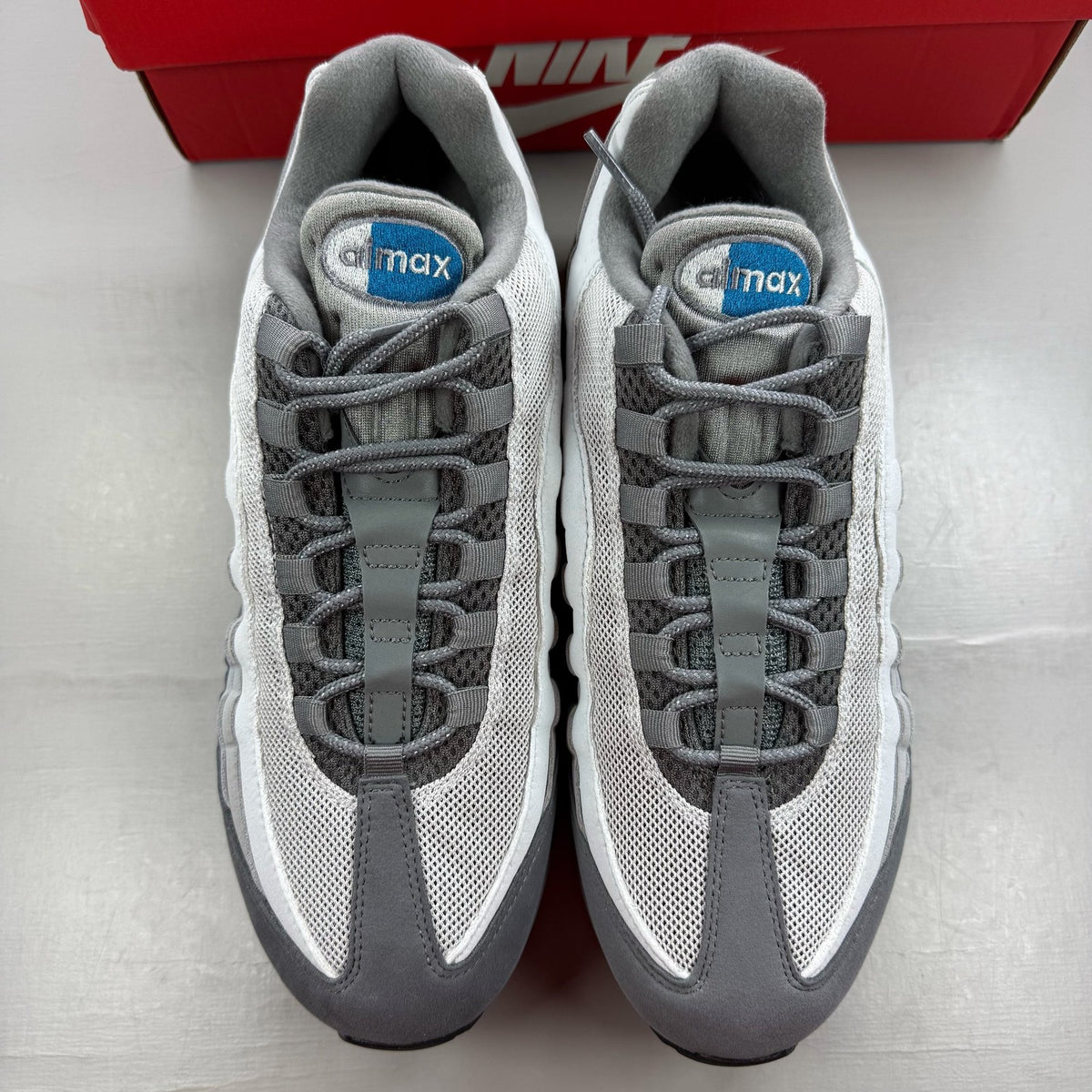 Nike Air Max 95 grey trainers with green accents and signature swoosh logo.