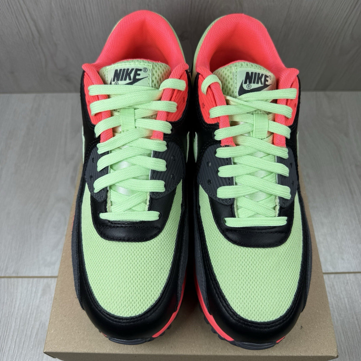 Nike Air Max 90 Essential green trainers with signature swoosh logo and mesh detailing.