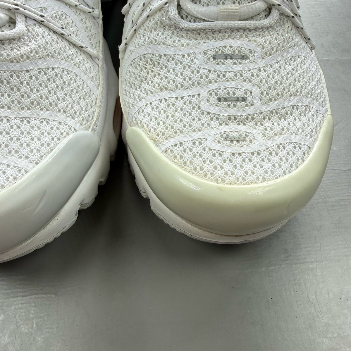 Nike footwear white trainers with orange accents and distinctive Air Max Plus TN design.