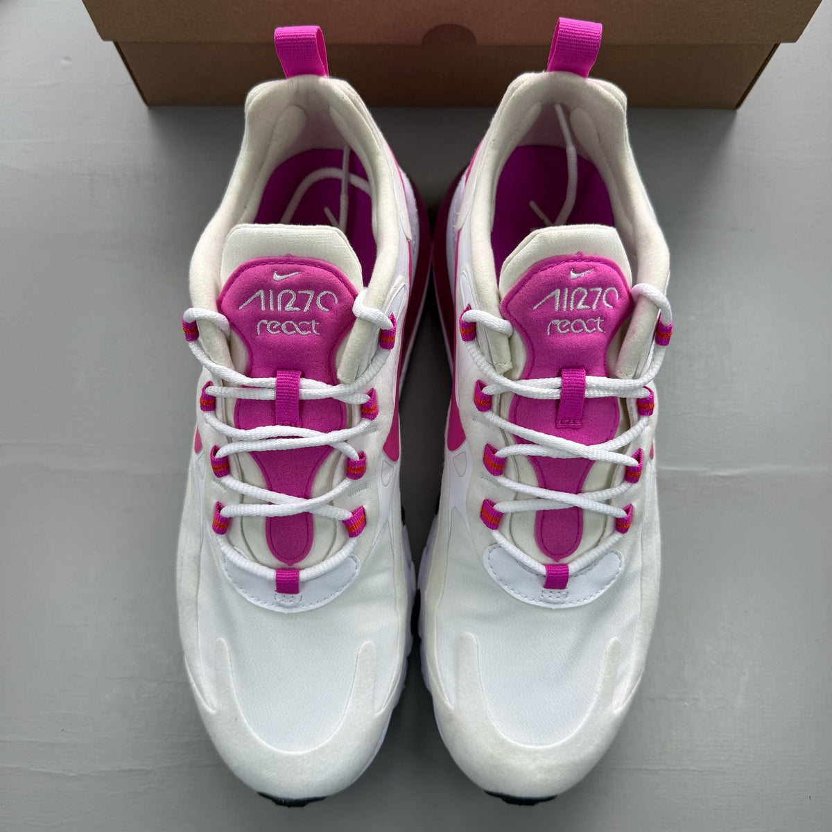 Nike white trainers with fire pink accents and Air Max logo detail.