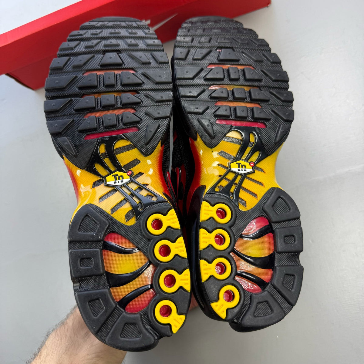 Nike Air Max Plus TN black with university gold and red accents, featuring iconic logo.