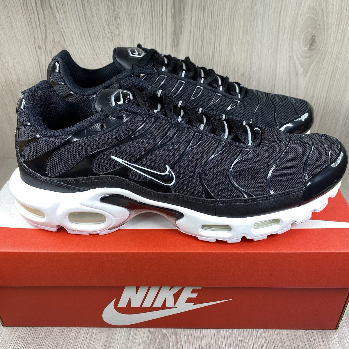 Nike Air Max Plus TN trainers black and white with signature logo and mesh detailing.