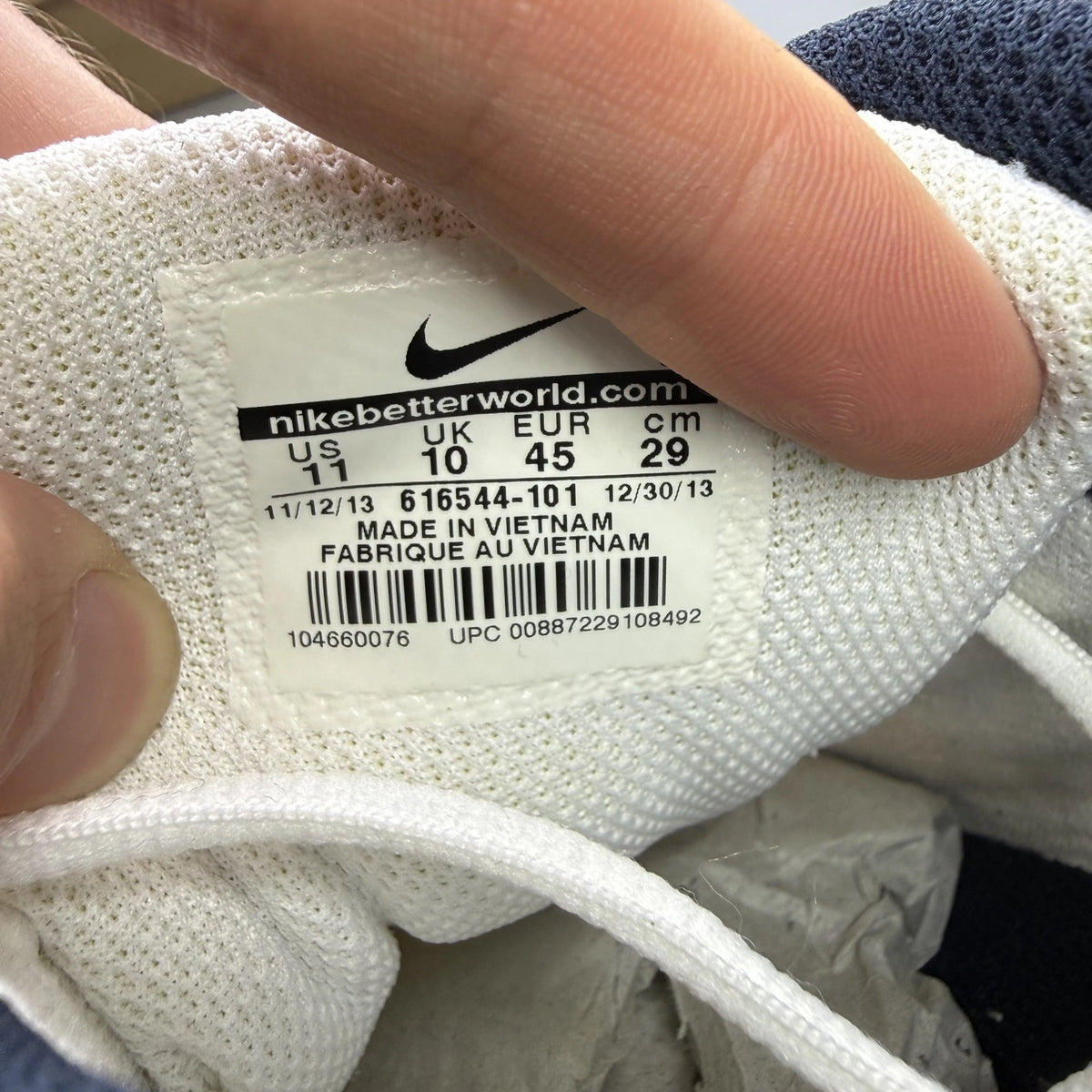 Nike white trainers with navy and black accents, featuring logo detailing and mesh material.