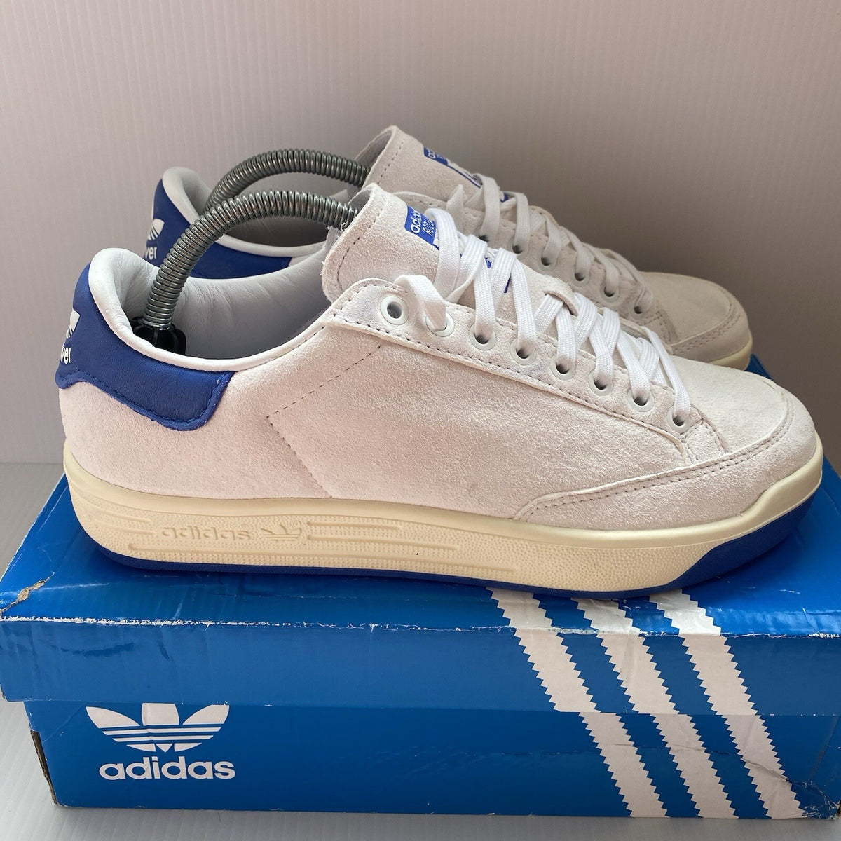 Adidas white trainers with blue and beige accents, featuring classic logo detail.