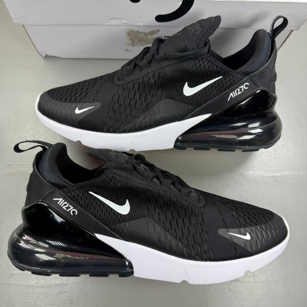 Nike Air Max 270 black trainers with white accents and logo detail.
