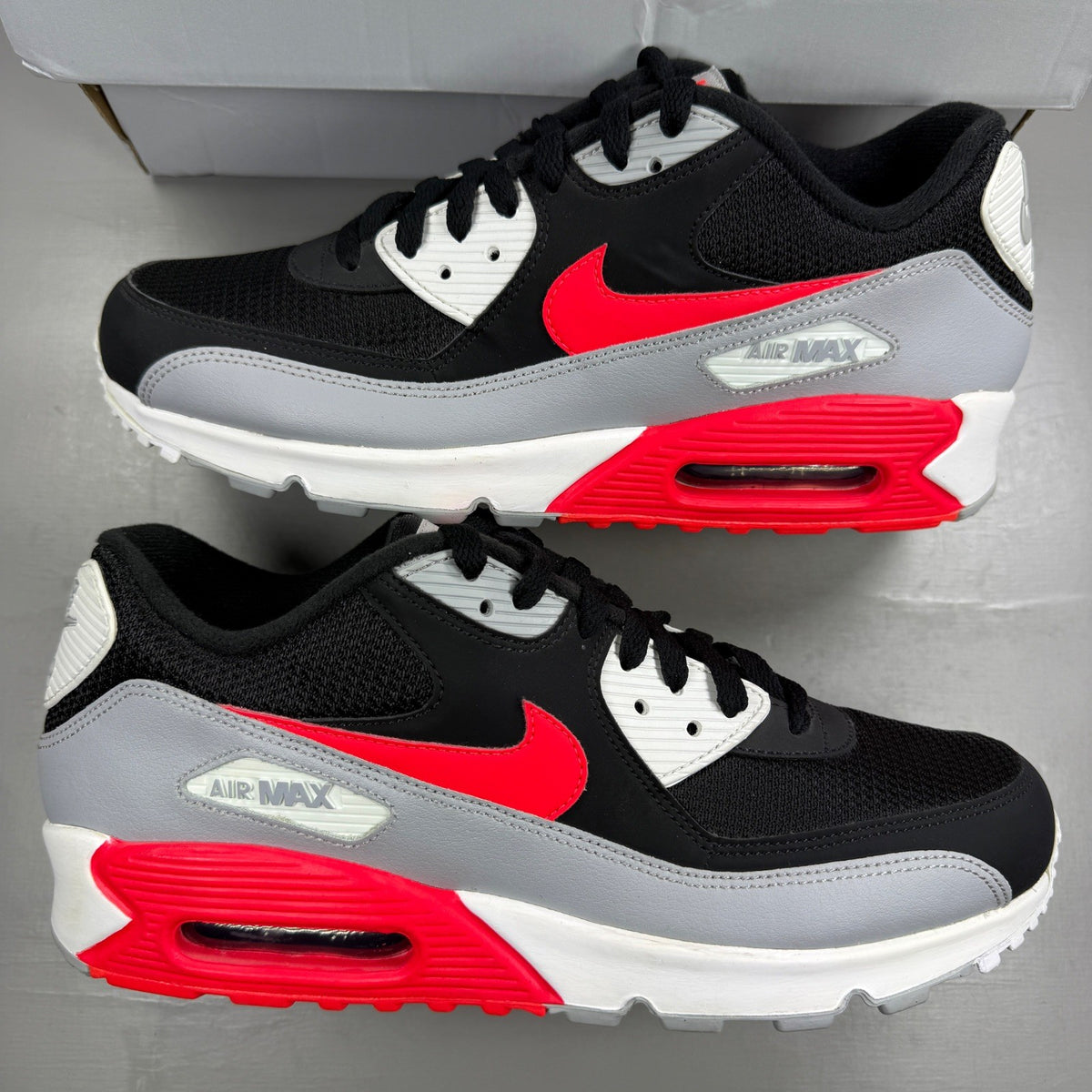 Nike Air Max 90 black sneakers with bright crimson accents and logo detailing.