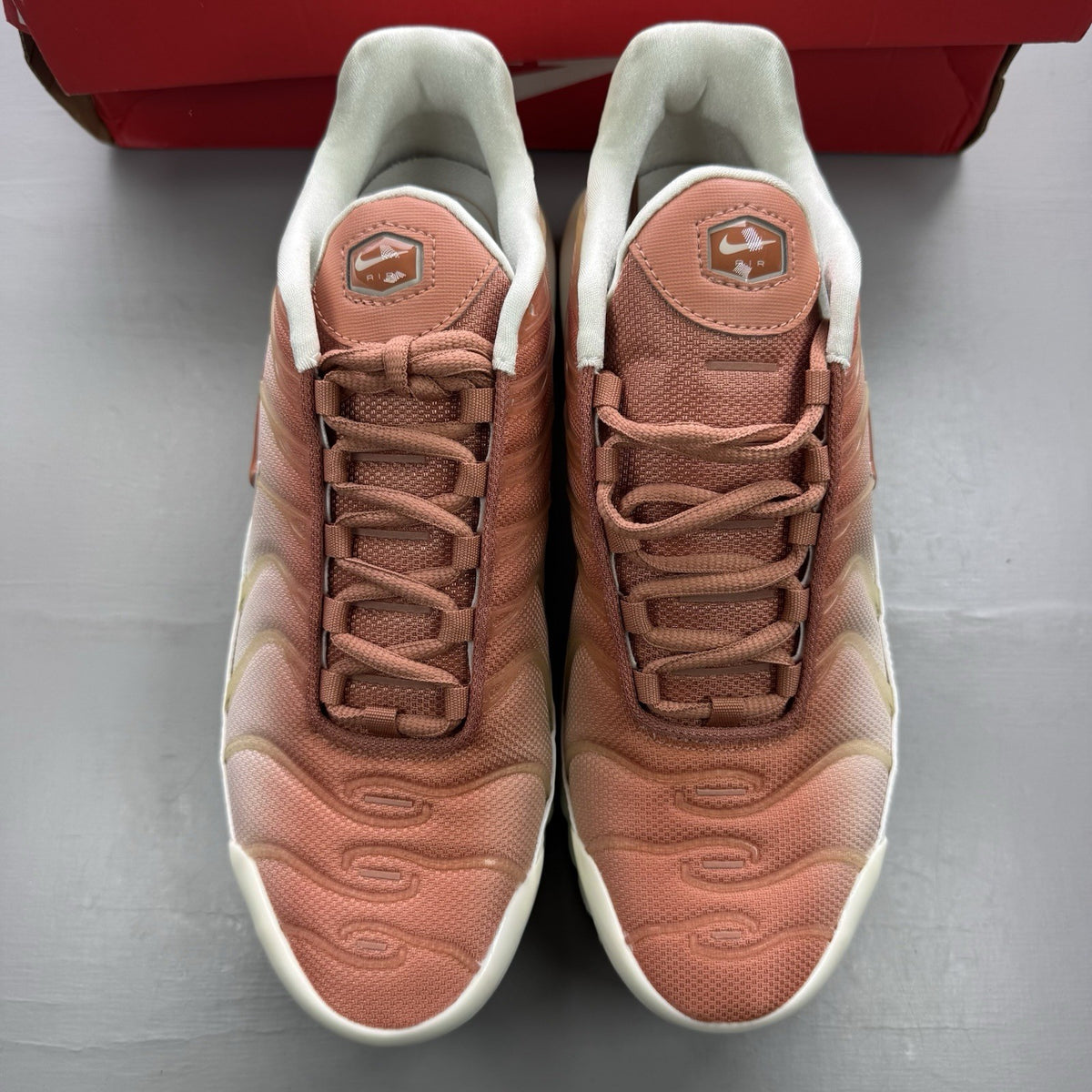Nike Air Max Plus TN white trainers with peach accents and signature swoosh logo.
