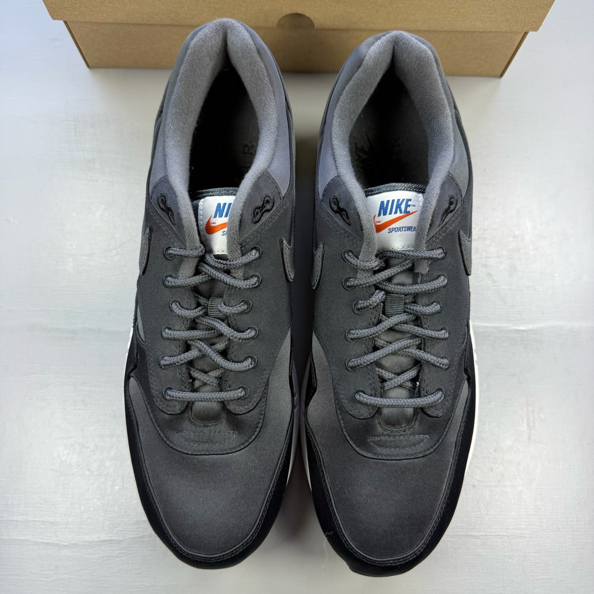 Nike black trainers with satin finish and pinwheel design details.
