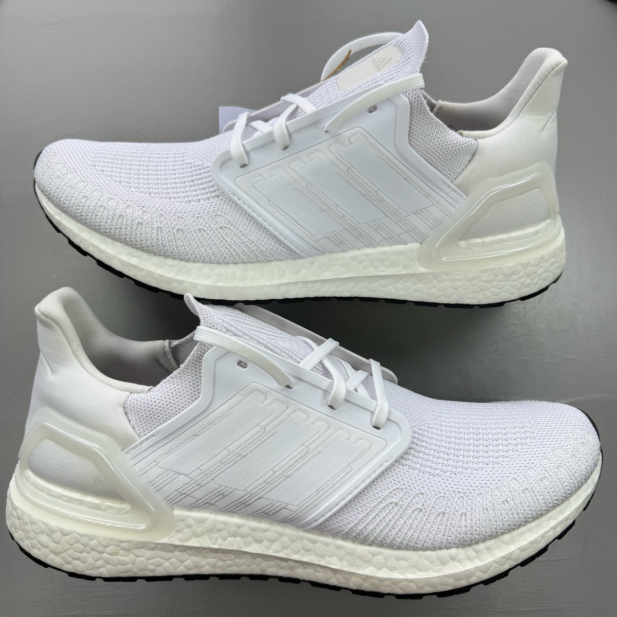 Adidas Ultraboost 20 white trainers with cloud cushioning and iconic three-stripe logo.