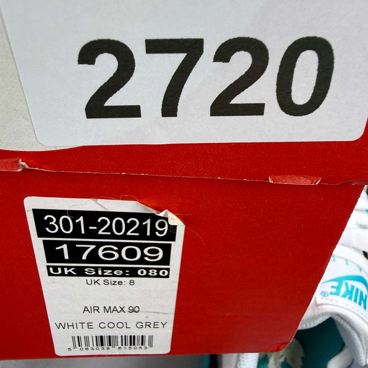 Nike Air Max 90 white trainers with teal accents and visible logo detail.