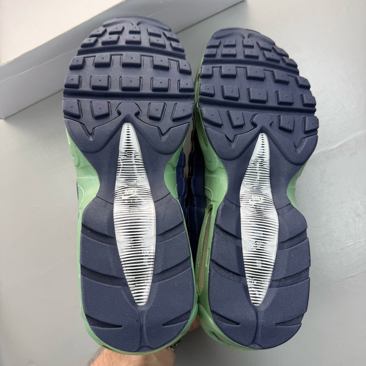 Nike Air Max 95 navy blue trainers with green accents and classic logo detailing.