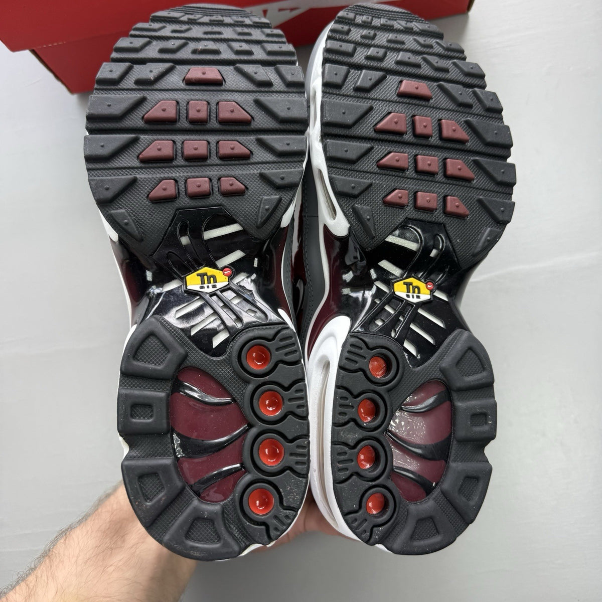 Nike Air Max Plus TN red trainers with grey and black accents, featuring signature logo.